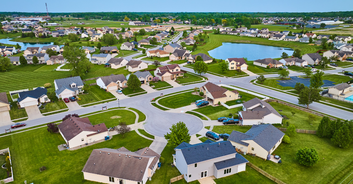 Aerial view of a suburban neighborhood with multiple houses, streets, and a pond, representing diverse communities under HOA management.