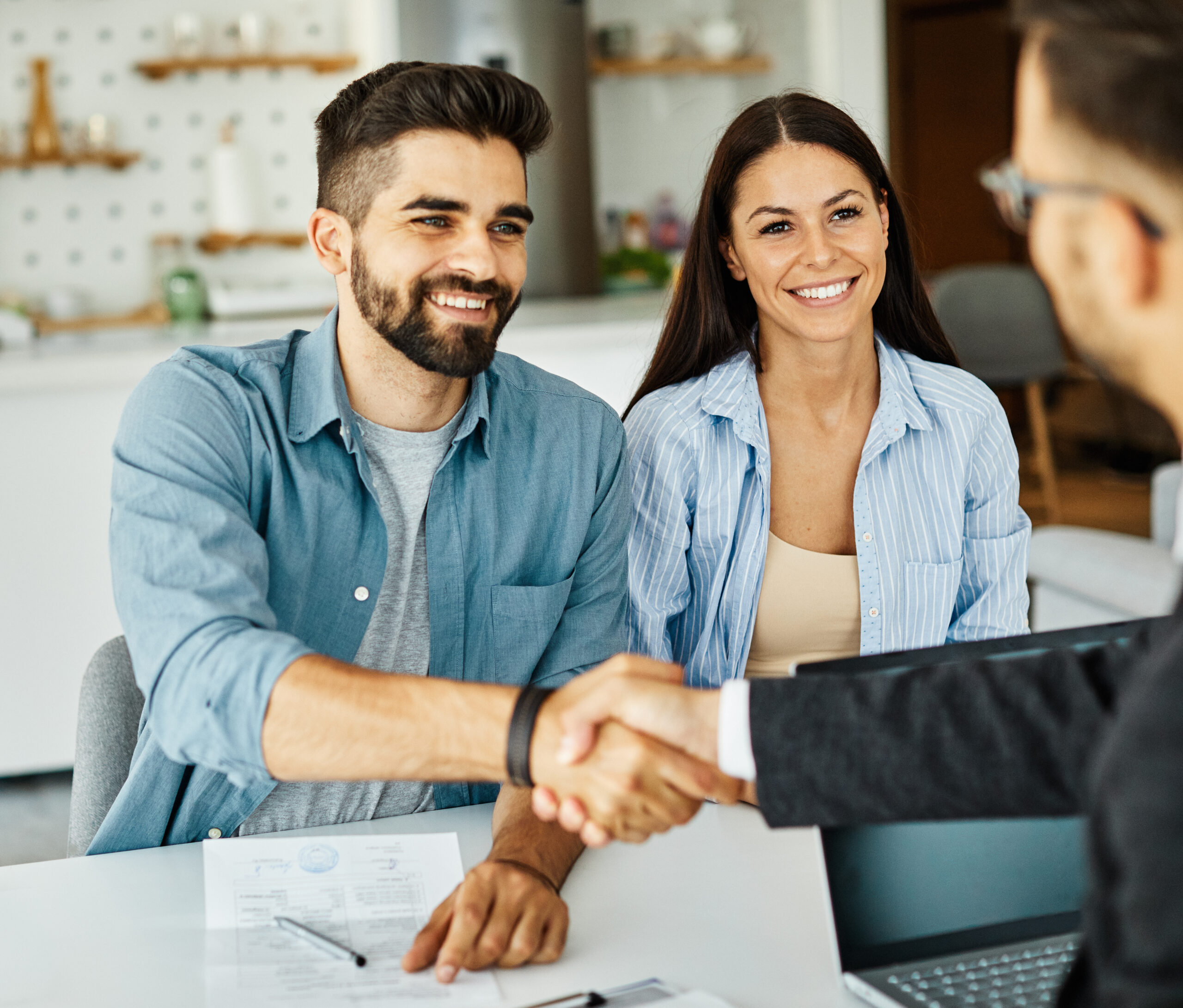 Real estate agent with couple shaking hands closing a deal and signing a contract