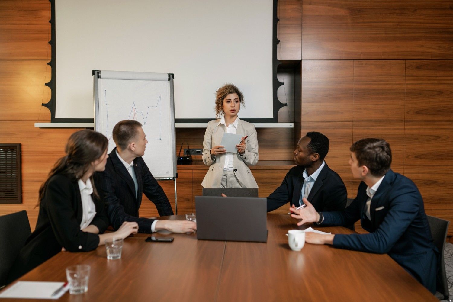 A local HOA management representative stands at the head of a conference table, presenting tailored community strategies to a focused board of directors during an intimate, collaborative meeting.