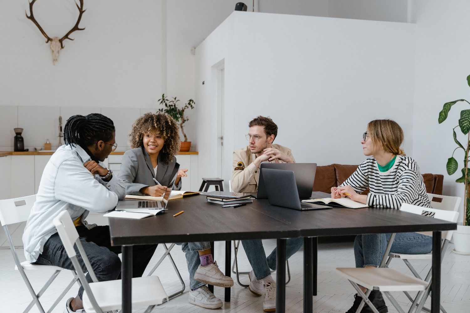 A diverse HOA leadership board sits around a table in a modern meeting space, actively discussing solutions to overcome community management challenges.